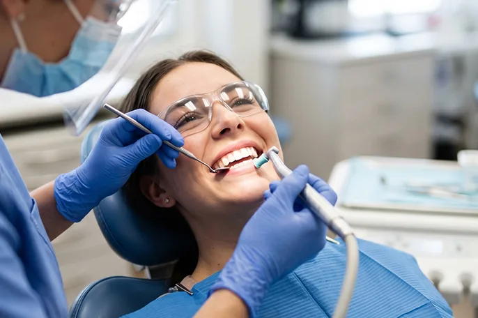 Close-up of a dental mirror and instrument beside a patient's teeth