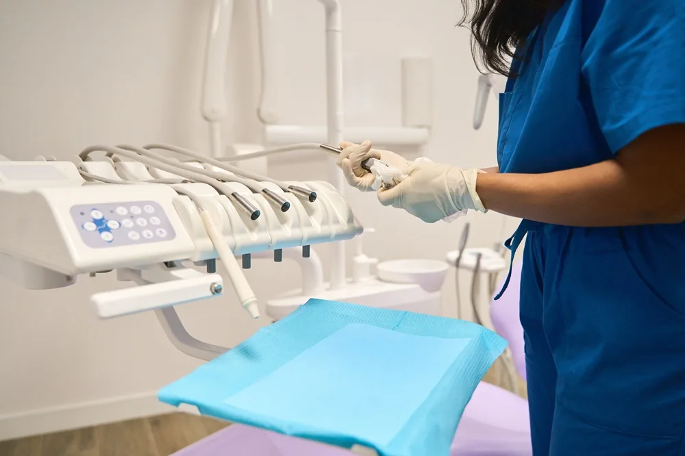 Dental professional holding a tooth model beside an instrument unit