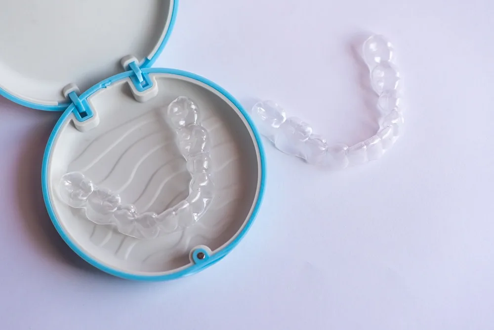 Two clear aligner trays beside an open blue storage case